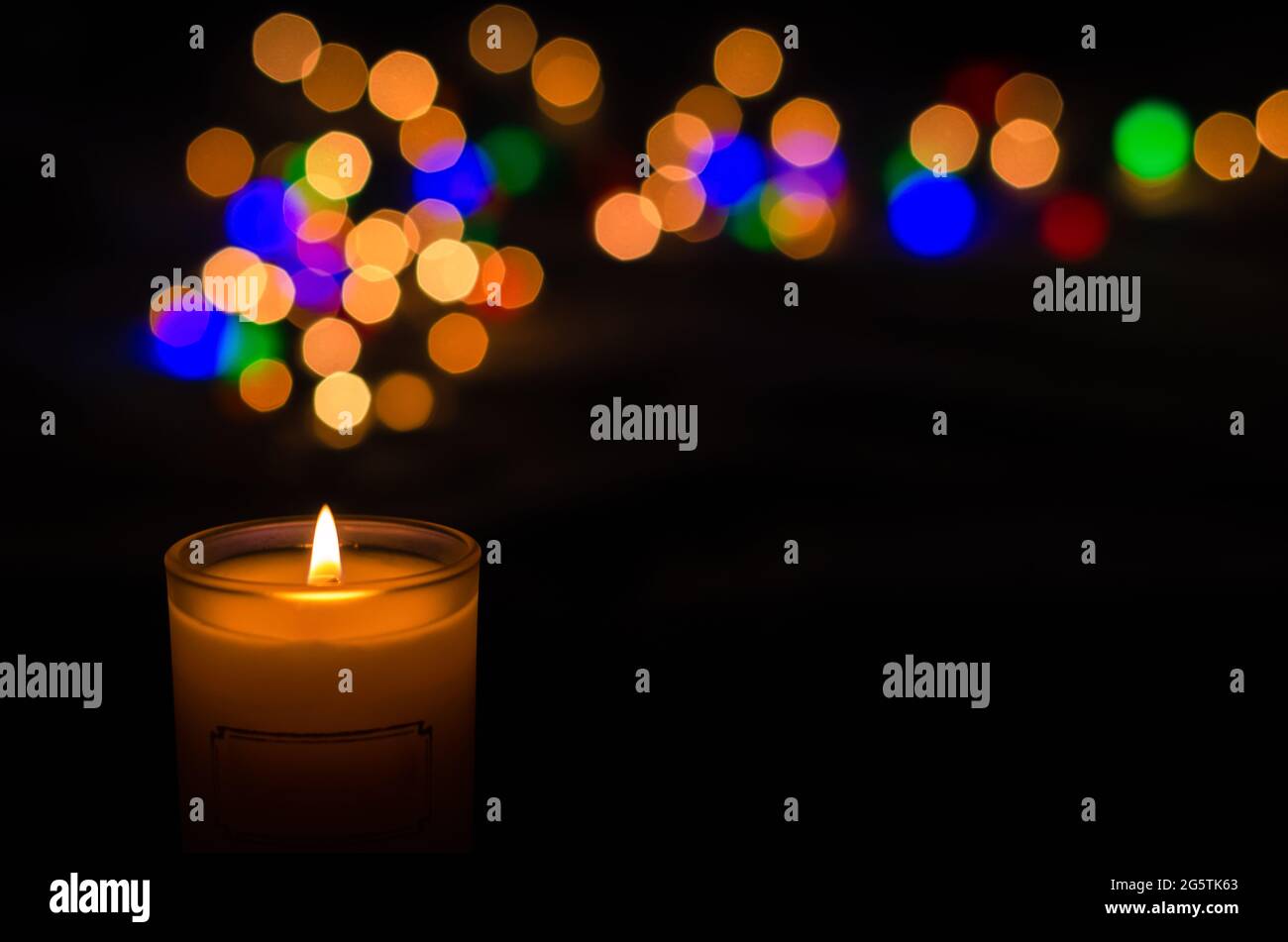 Candela aromatica con fiamma e bokeh di forma rotonda su sfondo scuro per ringraziamento e giorno di Natale. Foto Stock