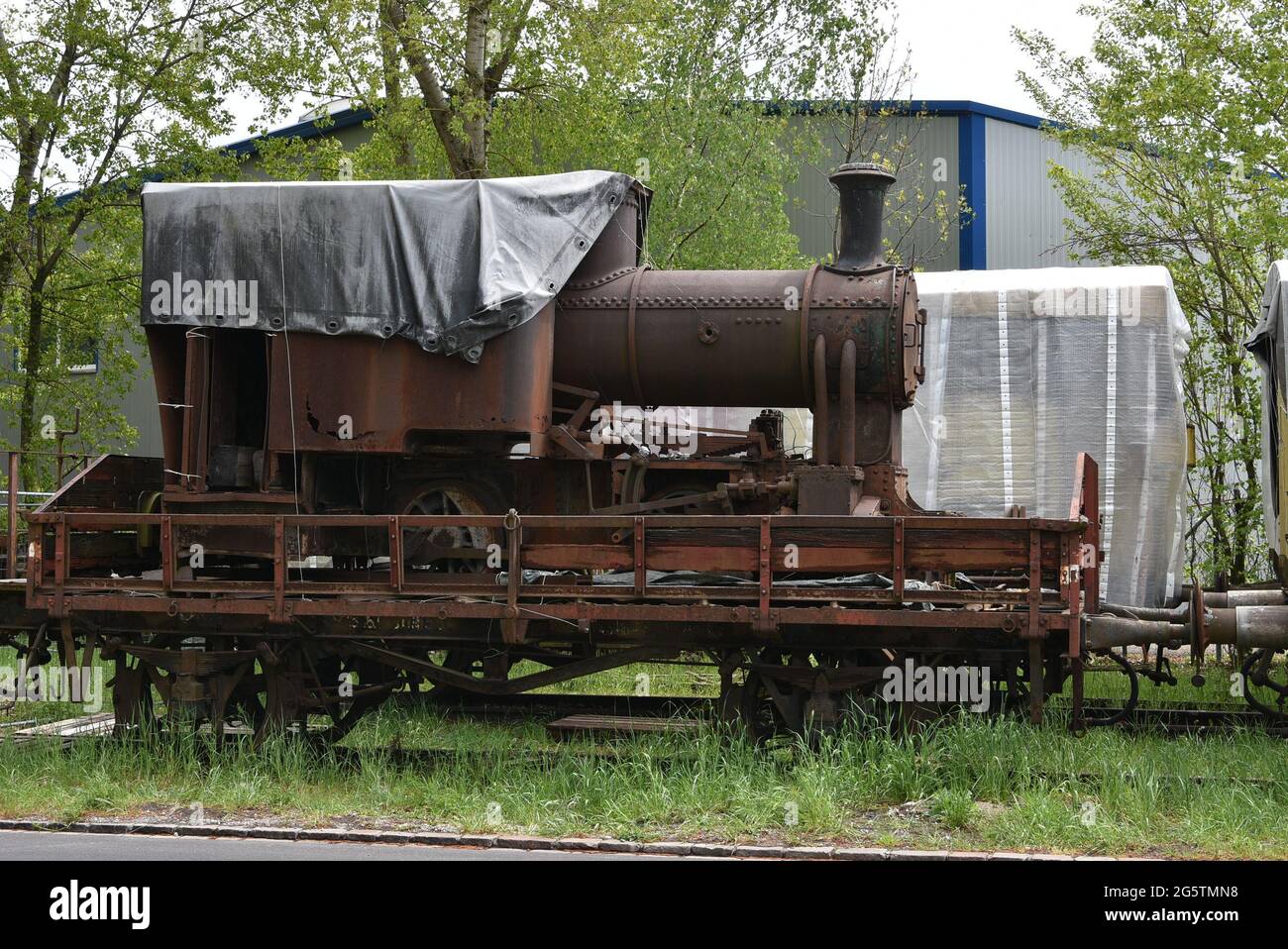La locomotiva a vapore per il trasporto di merci arrugginite è stata caricata su un vecchio carro in piedi su binari ferroviari ciechi nella zona industriale abbandonata. Foto Stock