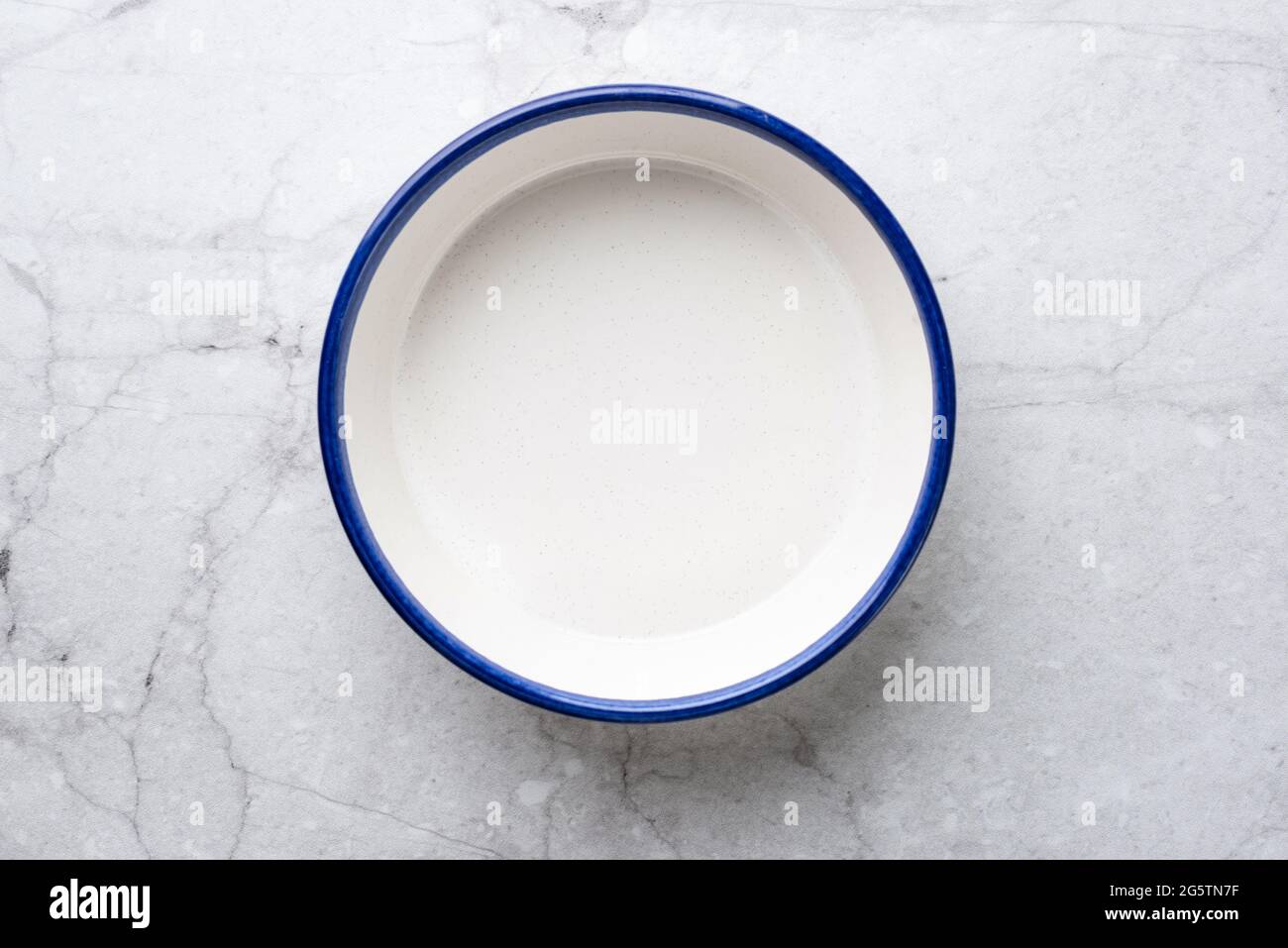 Piastra vuota in ceramica bianca con bordo blu su sfondo del tavolo in marmo bianco Foto Stock