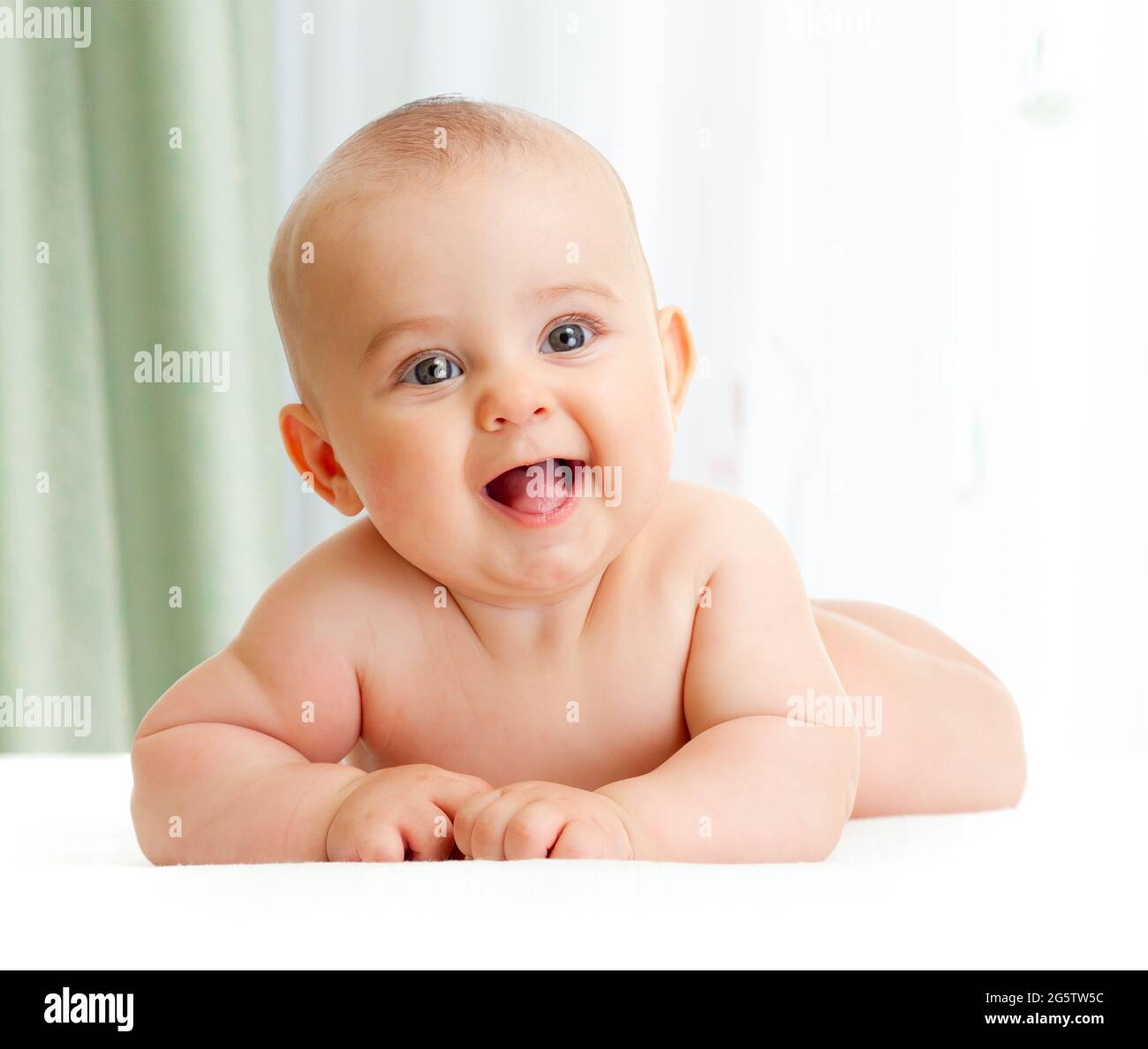 Adorabile bambino sorridente sdraiato in una camera da letto verde Foto Stock