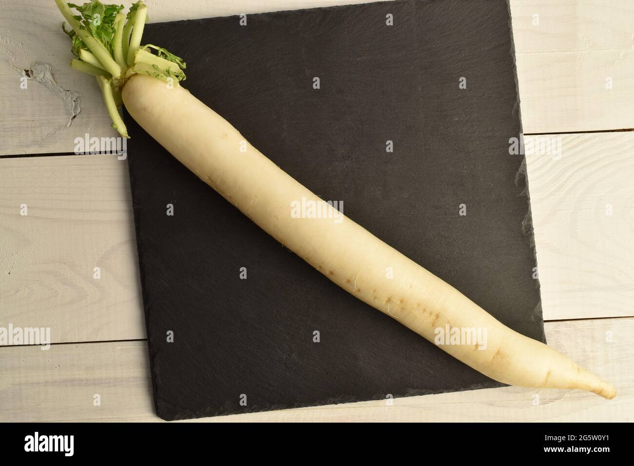 Un piatto organico, primo piano, su una tavola di servizio di ardesia, su un tavolo di legno bianco, vista dall'alto. Foto Stock