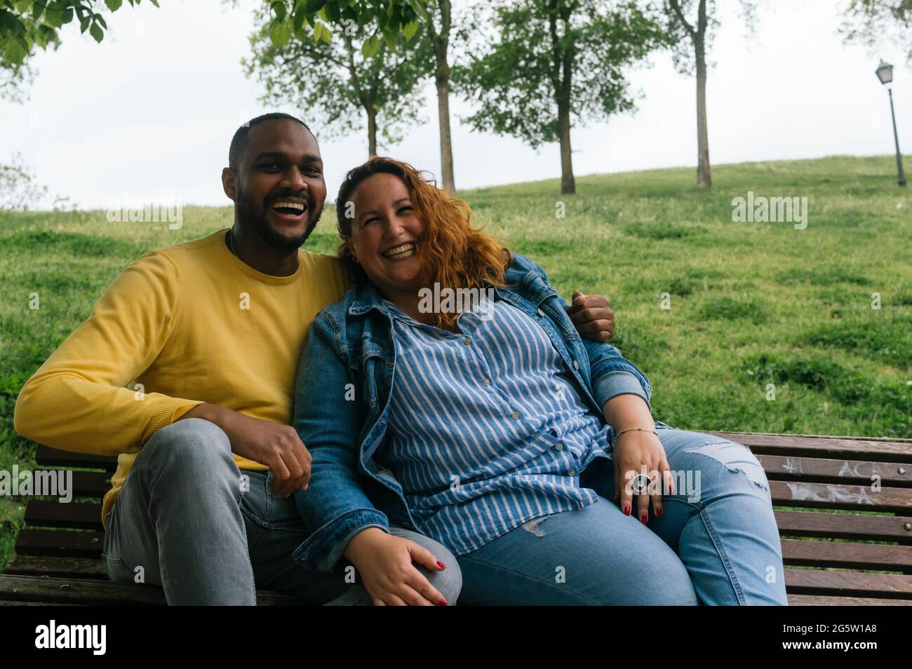 Giovane coppia interracial in amore baciando e ridendo in un parco Foto Stock