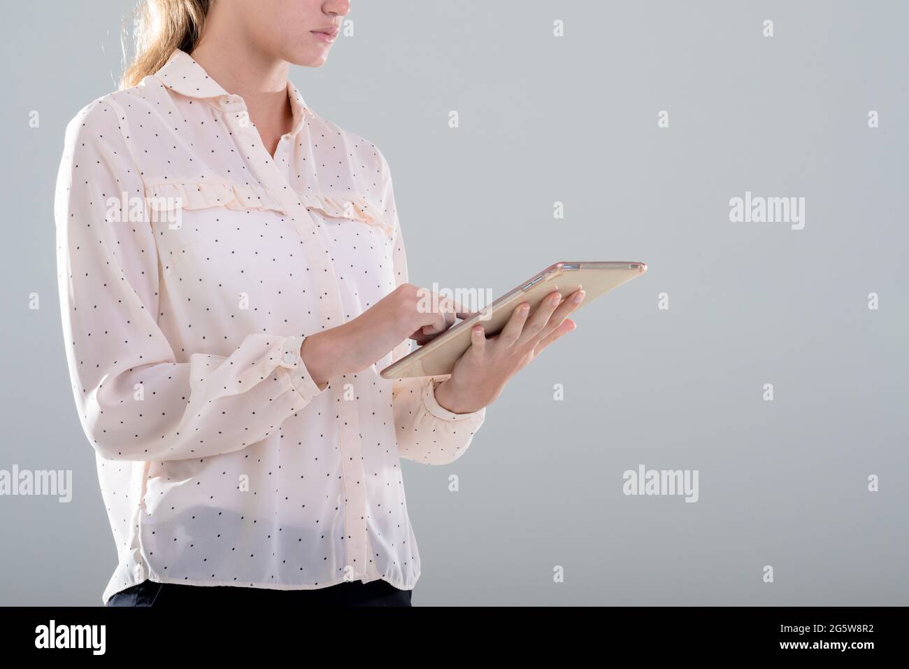 Donna d'affari caucasica che usa un tablet digitale, isolata su sfondo grigio Foto Stock