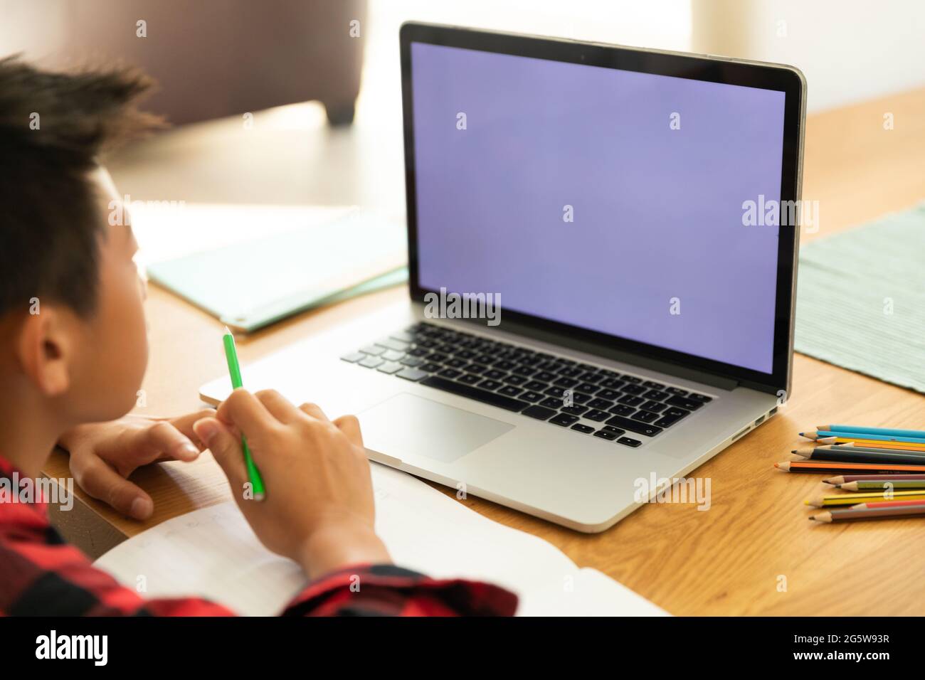 Ragazzo asiatico che usa un computer portatile con schermo vuoto a casa Foto Stock