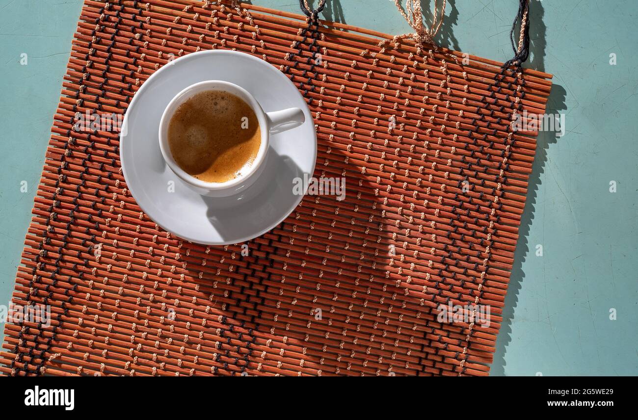 Caffè del mattino appena preparato, su un posizionamento di bambù e sulla tavola di colore blu chiaro con segni di taglio, ombre dure, vista dall'alto Foto Stock