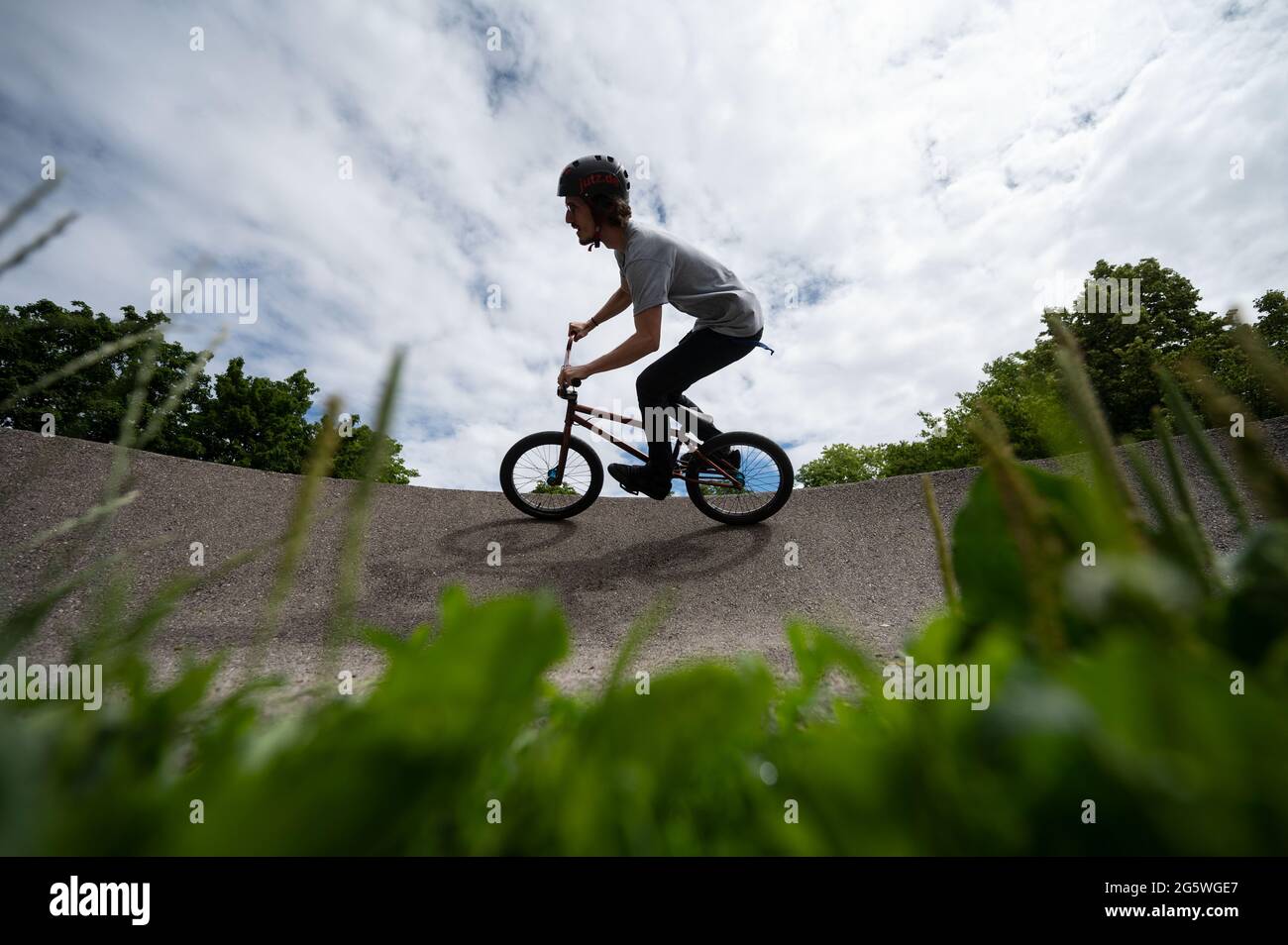 Gerlingen, Germania. 30 giugno 2021. Un dipendente di un centro giovanile guida un BMX su una pista di pompaggio. I Pumptracks sono in cima alla lista in molte comunità, e non solo tra i ciclisti. La pandemia di Corona ha ancora una volta stimolato il boom edilizio. Credit: Marijan Murat/dpa/Alamy Live News Foto Stock