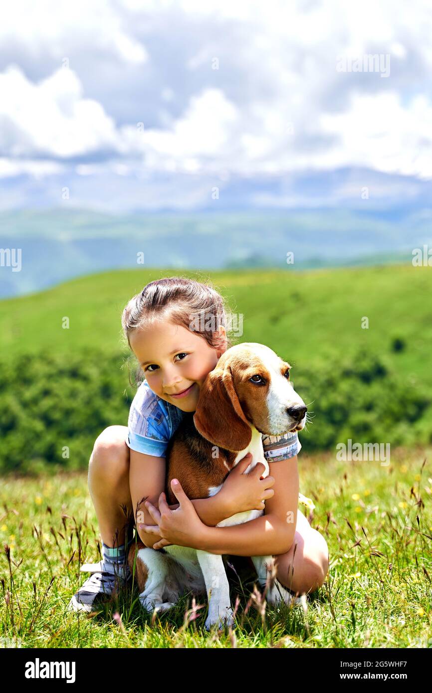bambina divertente con un cane in montagna Foto Stock