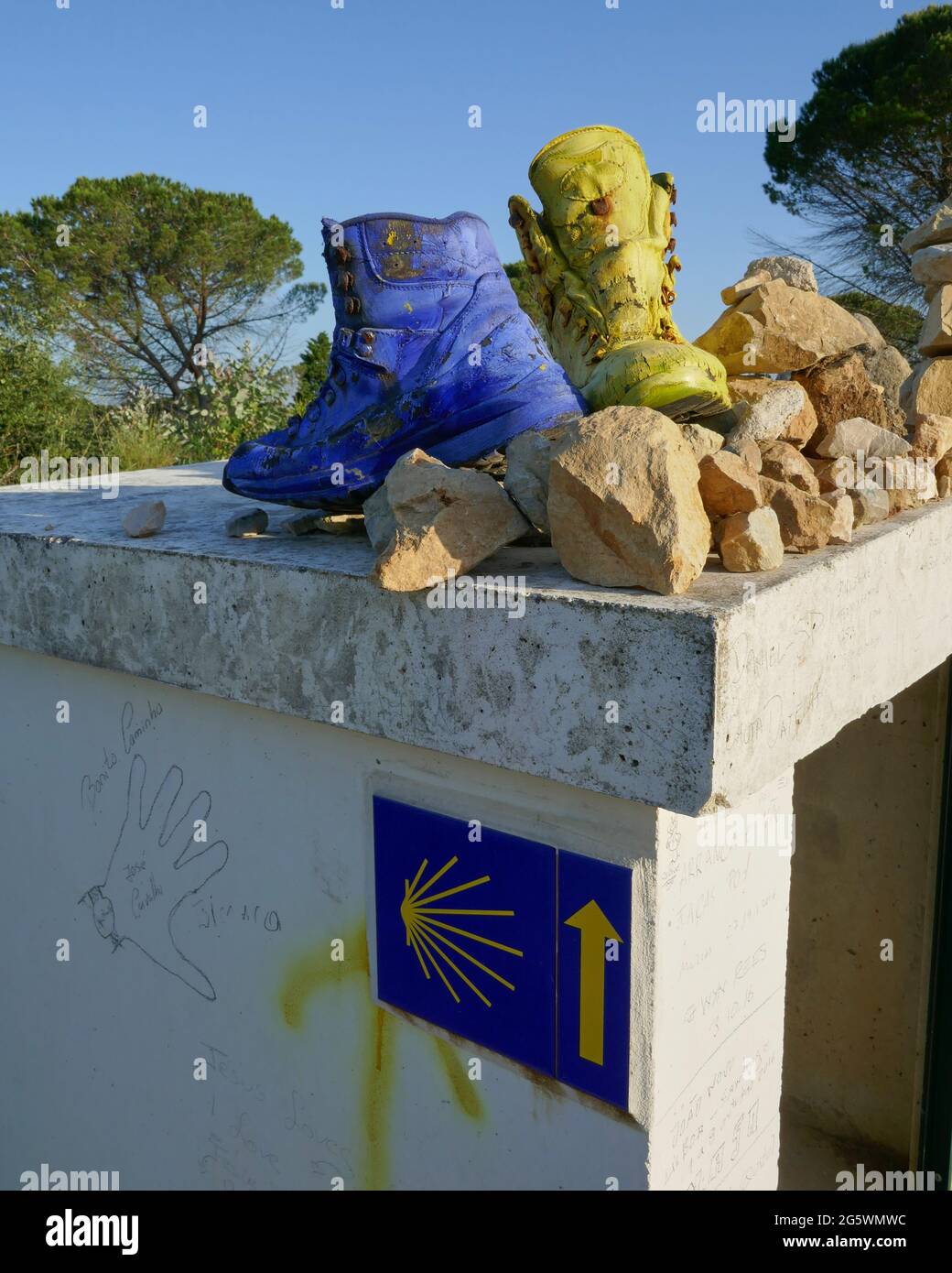 Vecchi stivali dipinti in giallo e blu, a sinistra come segno di riferimento sul Camino de Santiago Foto Stock
