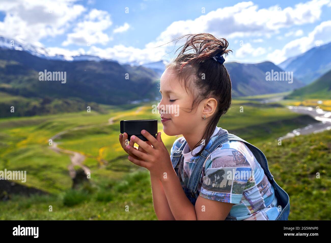 divertente bella ragazza tiene una tazza e bevande tè in montagna Foto Stock