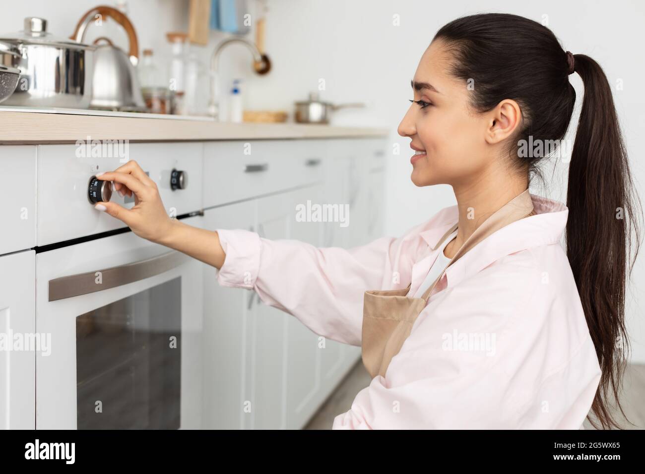 Donna sorridente che usa cibo di cottura della stufa in cucina Foto Stock