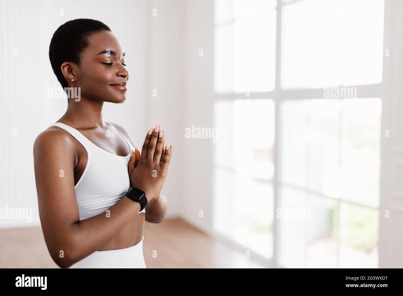 Donna nera meditando tenendo insieme le mani nella posa di preghiera Foto Stock