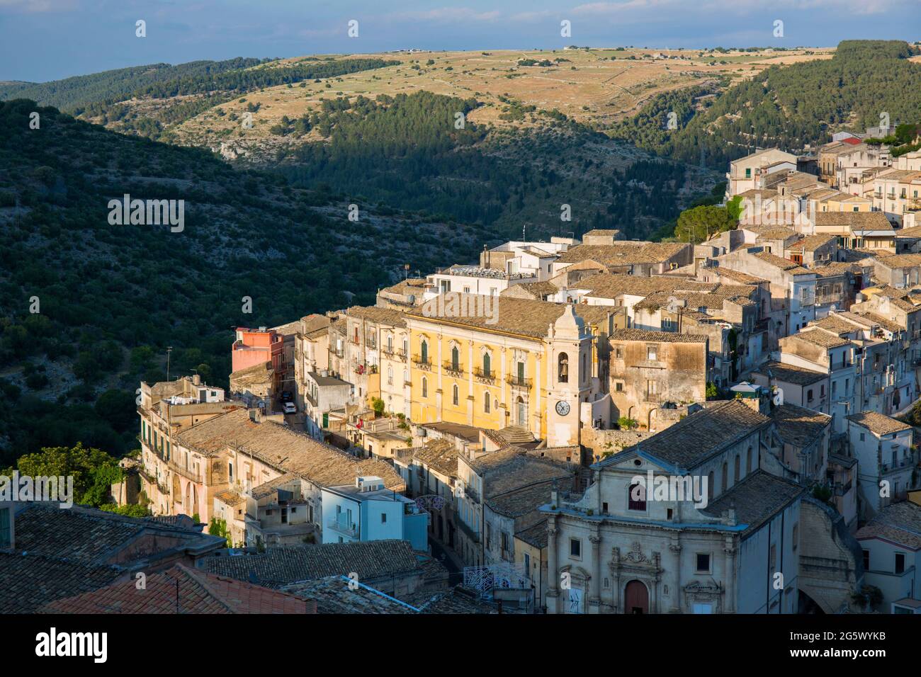 Ragusa, Sicilia, Italia. Vista sui tetti panoramici di Ragusa Ibla, tramonto, case aggrappate a ripide colline sopra gola boscosa. Foto Stock