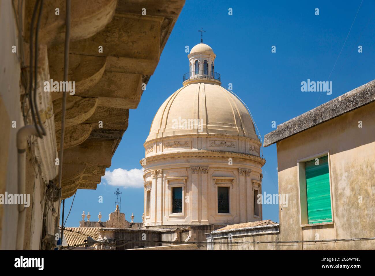 Noto, Siracusa, Sicilia, Italia. Vista lungo la stradina illuminata dal sole fino alla cupola ricostruita della Cattedrale barocca di San Nicolò. Foto Stock