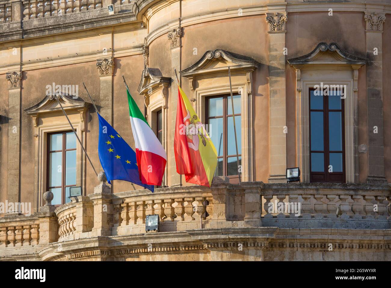 Noto, Siracusa, Sicilia, Italia. Le bandiere della Sicilia, dell'Italia e dell'Unione europea che volano dal balcone del Palazzo Ducezio, oggi Municipio. Foto Stock