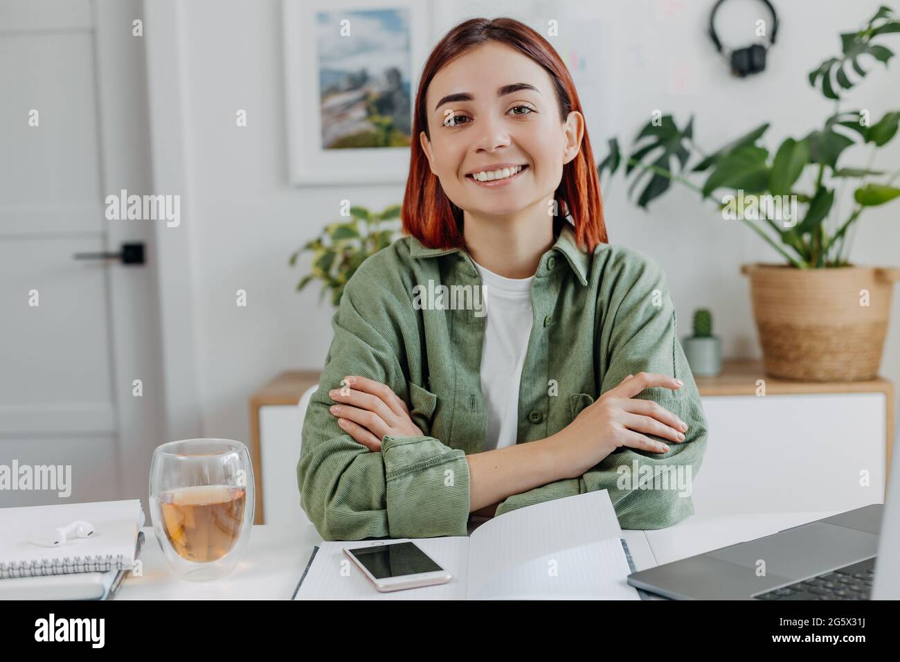 Ritratto di giovane donna sorridente che lavora a casa con un computer portatile. Donna d'affari rilassata con una tazza di tè. Concetto di business online o di comunicazione, freel Foto Stock