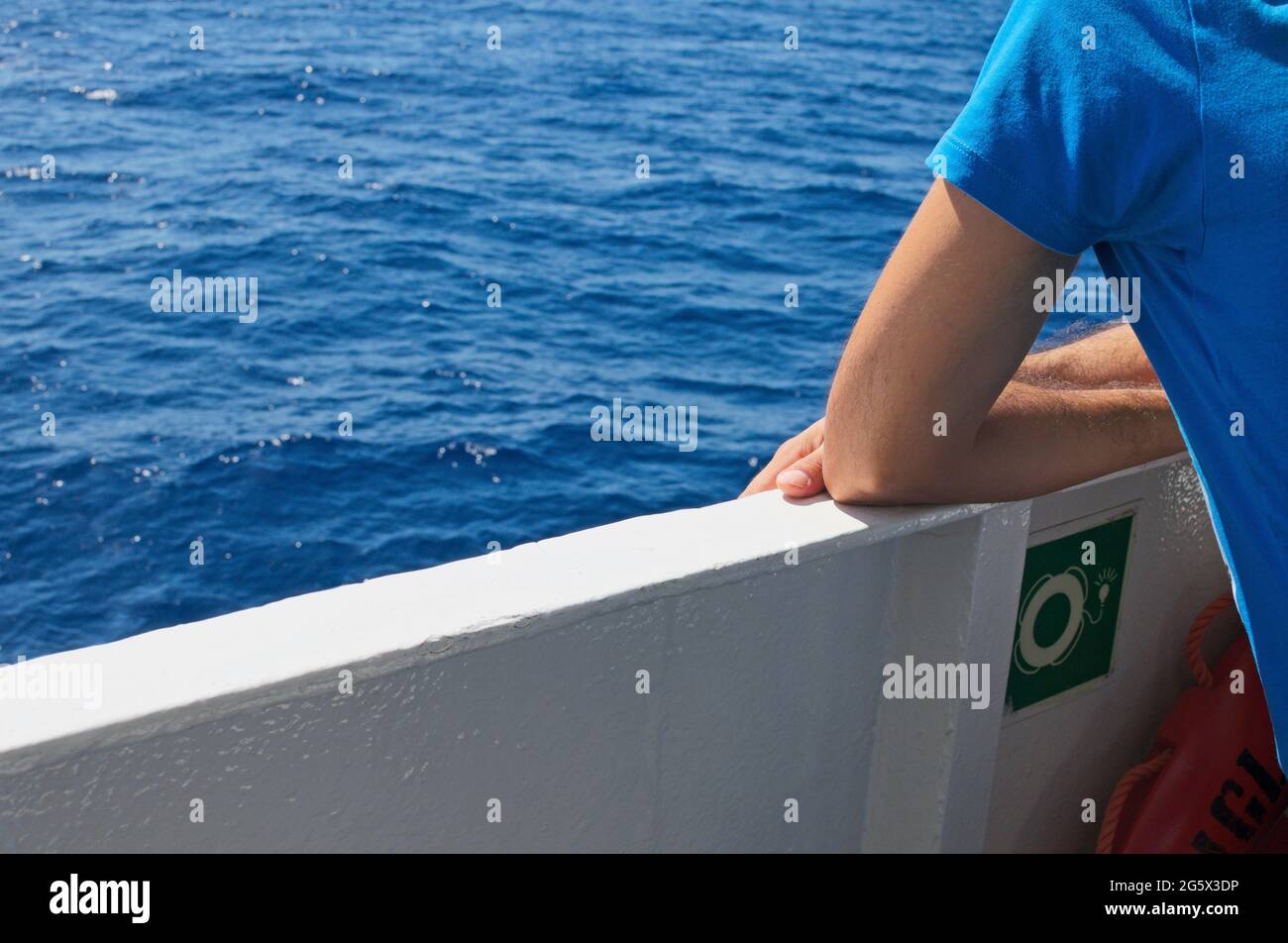 giovane appoggiato alla ringhiera di un traghetto passeggeri che guarda il mare Foto Stock