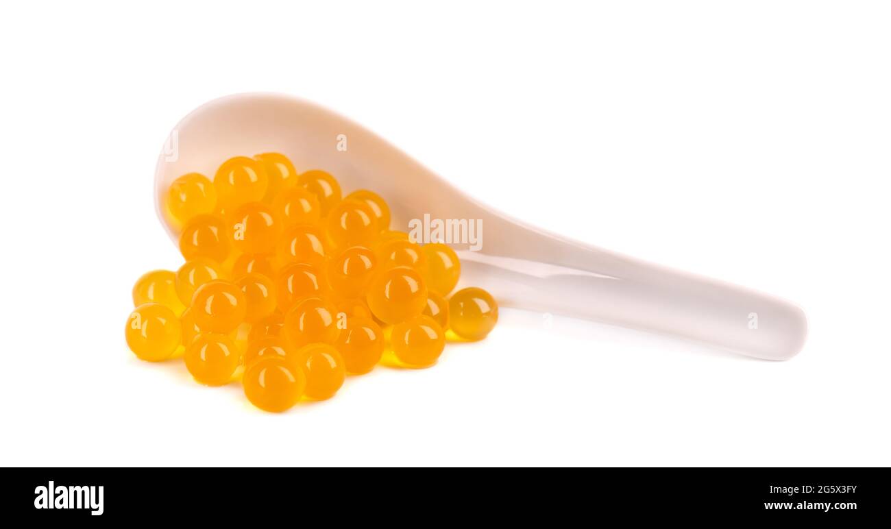 Perle di tapioca gialle per il tè delle bolle isolate su sfondo bianco. Perle di tapioca in cucchiaio di ceramica. Foto Stock