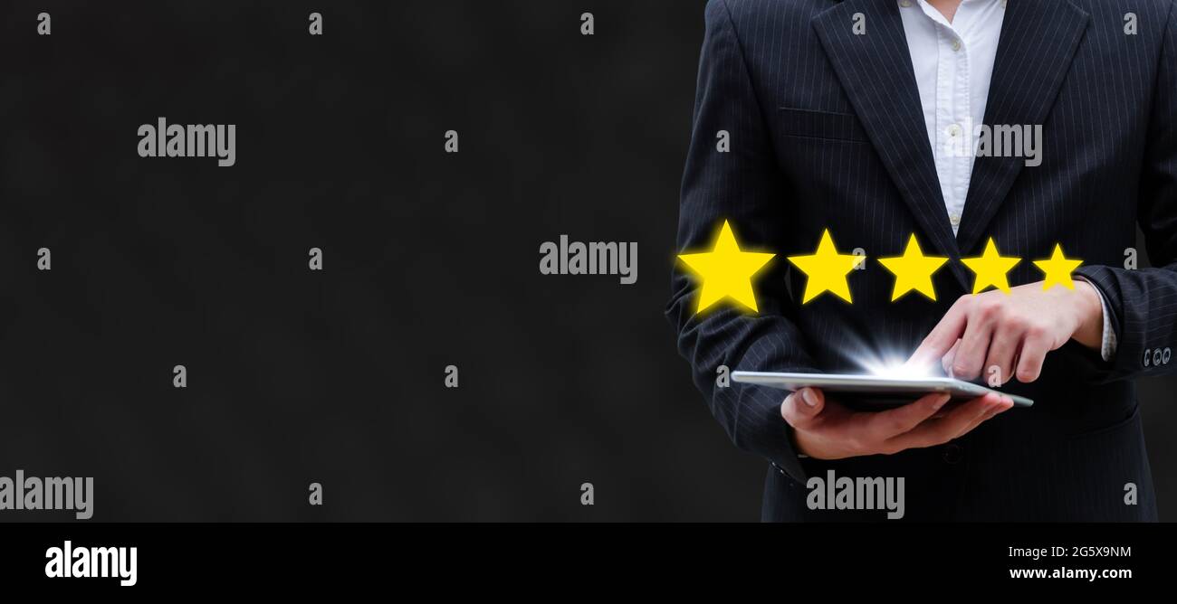 banner largo. valutazione a 5 stelle. cliente uomo d'affari mano toccare sul tablet mobile con il pulsante a cinque stelle per rivedere la buona valutazione, il marketing digitale, buono Foto Stock