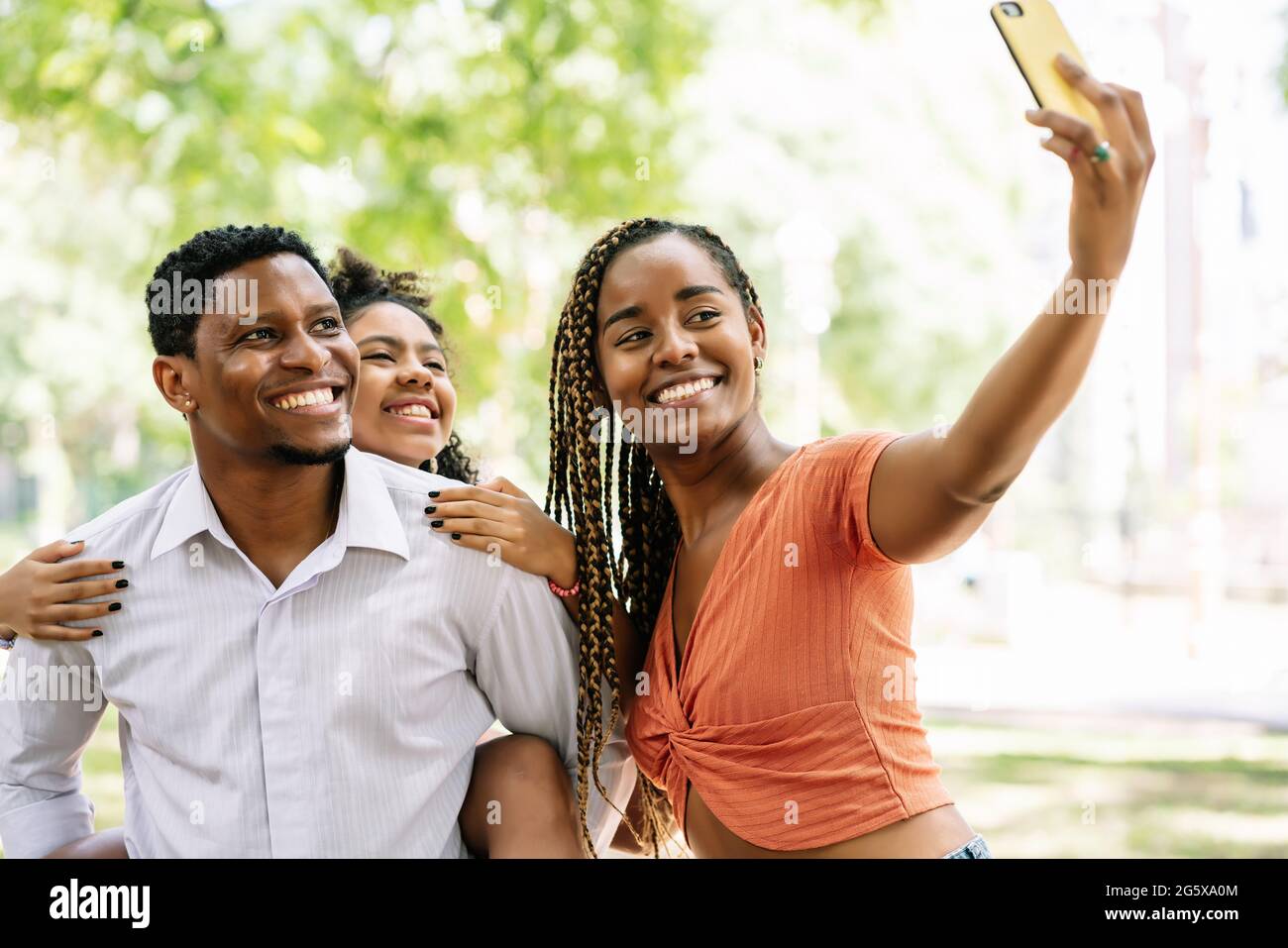 Famiglia che prende un selfie con un telefono cellulare al parco. Foto Stock