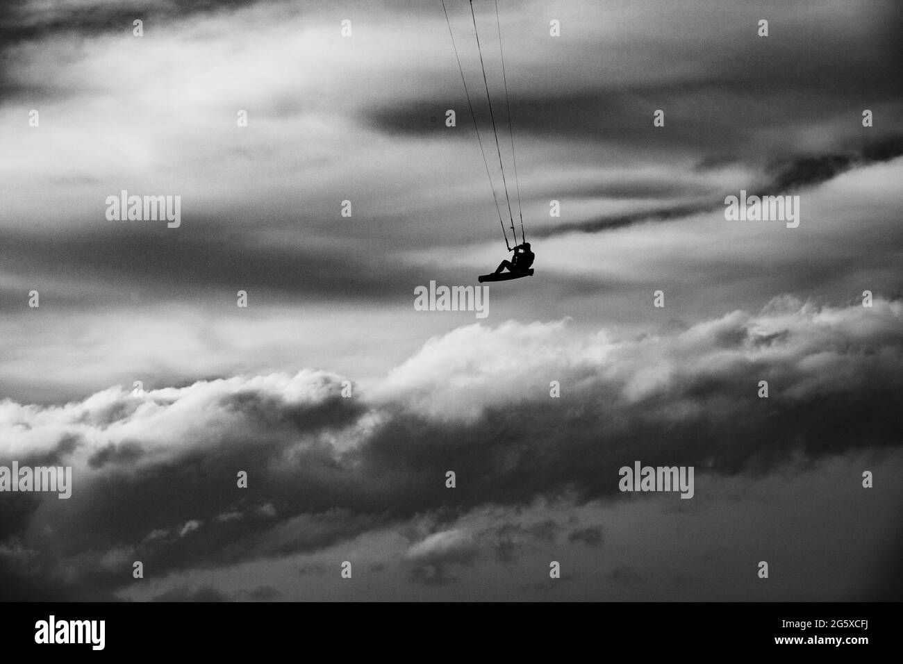 Kite surf in tempesta in inverno con salti estremi. Navigazione sul cloud. Drammatico bianco e nero. Foto Stock