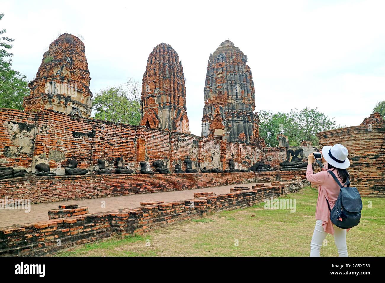 Visita femminile Foto di Stupas e Buddha immagini rovine nel tempio antico di Wat Mahathat, Ayutthaya Historical Island Thailandia Foto Stock