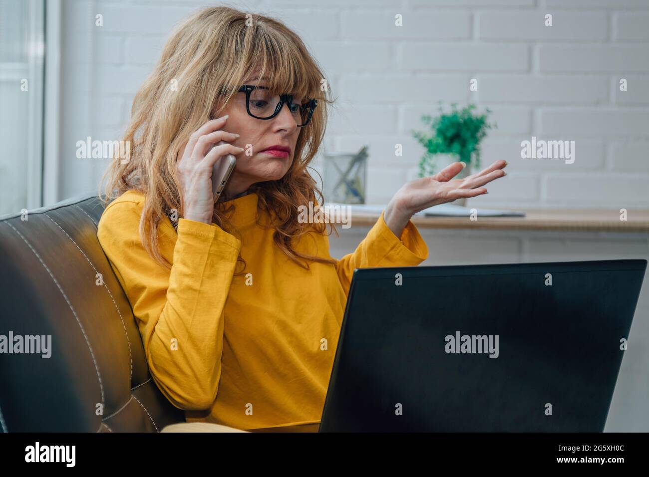 donna che consulta dal telefono cellulare l'ignoranza o problemi con il computer Foto Stock