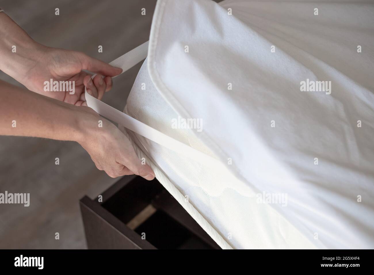 Una donna mette un coprimaterasso sul letto. Dormite di qualità su un comodo letto. Foto Stock