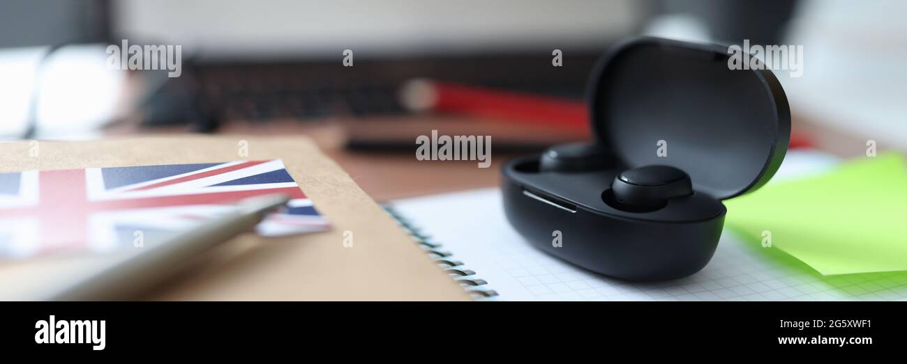 Le cuffie wireless nere nella scatola si siedono sul tavolo accanto a. notebook e penna Foto Stock