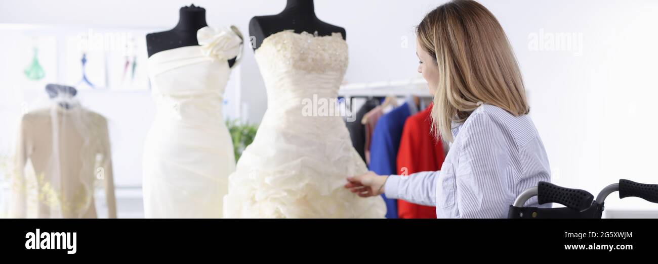 Donna in sedia a rotelle esamina l'abito da sposa in salone Foto Stock