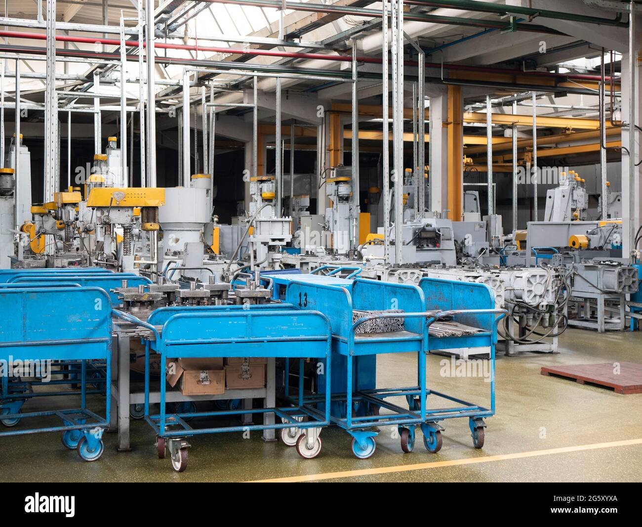 Ambiente interno del pavimento della fabbrica. Carri blu con pezzi in metallo, unità industriali in officina. Officina di produzione Foto Stock