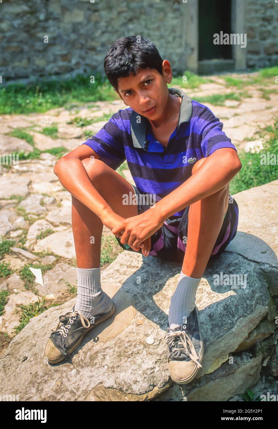 VELIKO TARNOVO, BULGARIA - giovane Rom seduto su un muro di pietra. Ragazzo Gyspy. Foto Stock