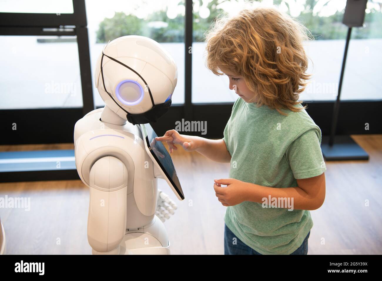 un piccolo ragazzo intelligente comunica con la tecnologia robot assistant per l'istruzione moderna, la robotica Foto Stock