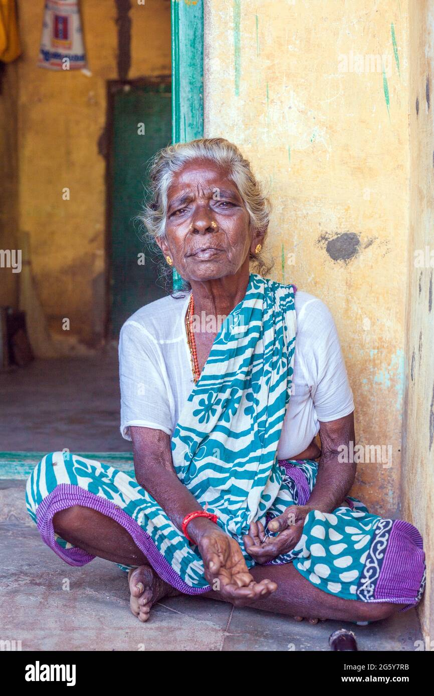 Ritratto di anziana signora indiana con i capelli grigi seduti nella porta - pregando con mano estensibile, Puducherry (Pondicherry), Tamil Nadu, India Foto Stock