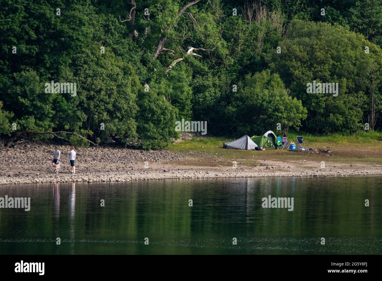 Loch Venachar, Loch. Lomonnd e Trossachs National Park, Scozia, Regno Unito. 30 giugno 2021. NELLA FOTO: Le tende si accopicchiano sul lato del lago e la gente fuori sull'acqua paddle boarding, kayak, nuoto selvaggio e godendo il caldo tempo estivo durante un tempo in cui i laghi scozzesi sono esauriti di acqua. La grande spiaggia di stoney è rivelata intorno al lago che normalmente sarebbe completamente sotto l'acqua ma con il tempo asciutto e caldo lungo non ci è niente sostituire l'acqua che evapora. Credit: Colin Fisher/Alamy Live News Foto Stock