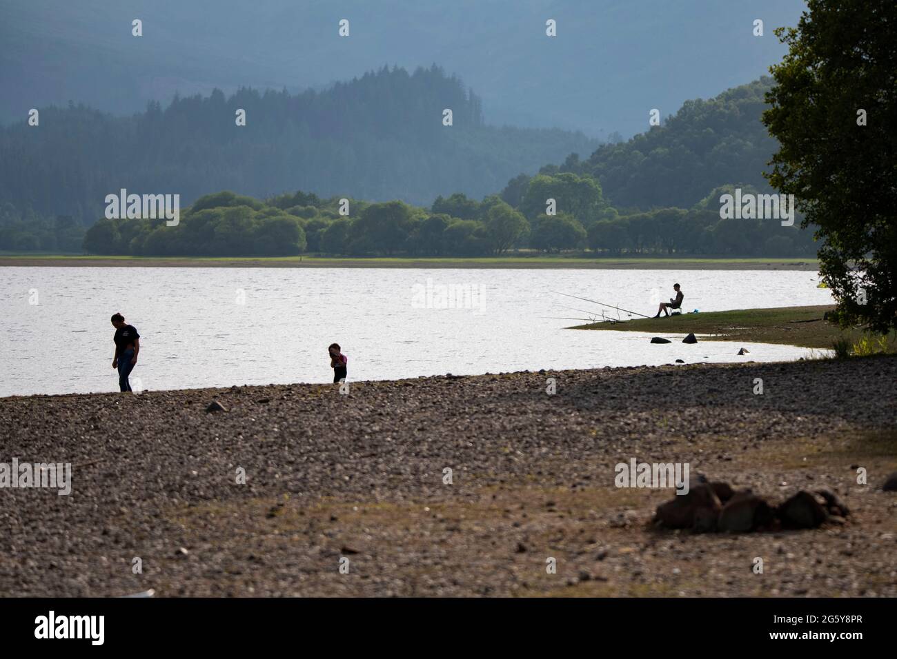 Loch Venachar, Loch. Lomonnd e Trossachs National Park, Scozia, Regno Unito. 30 giugno 2021. NELLA FOTO: Le persone che si trovano sull'acqua possono fare paddle boarding, kayak, nuoto selvaggio e godersi il caldo clima estivo durante un periodo in cui i laghi scozzesi sono impoveriti di acqua. La grande spiaggia di stoney è rivelata intorno al lago che normalmente sarebbe completamente sotto l'acqua ma con il tempo asciutto e caldo lungo non ci è niente sostituire l'acqua che evapora. Credit: Colin Fisher/Alamy Live News Foto Stock