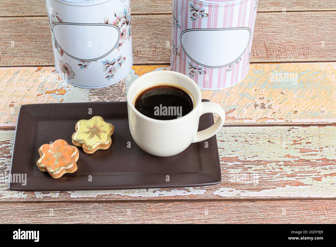 Biscotti al burro con vernice commestibile, accanto ad una tazza di caffè e due barattoli. Foto Stock