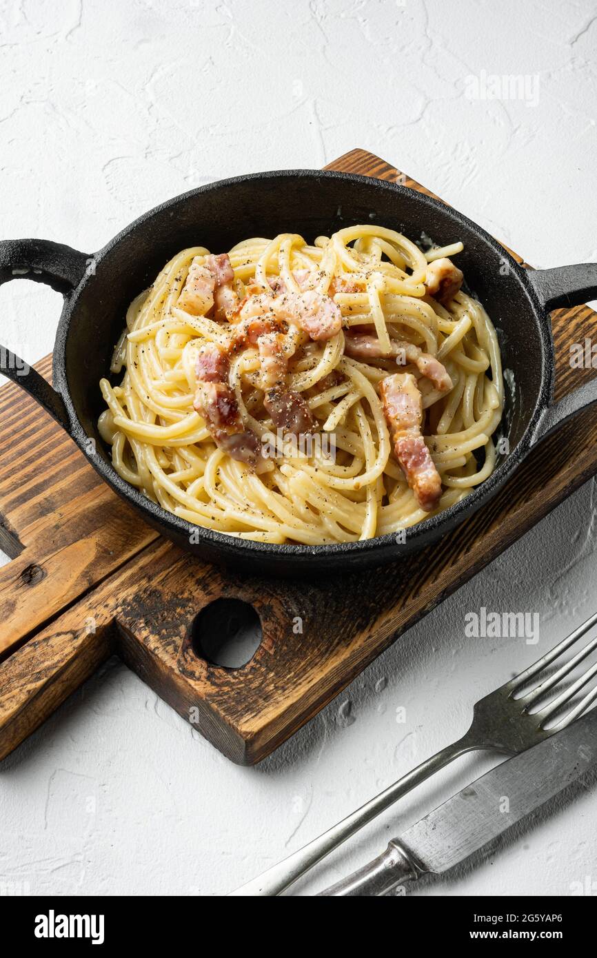 Classica pasta carbonara italiana fatta in casa con pancetta, uova, set di  Parmigiano, in padella di ghisa, su una superficie di pietra bianca Foto  stock - Alamy