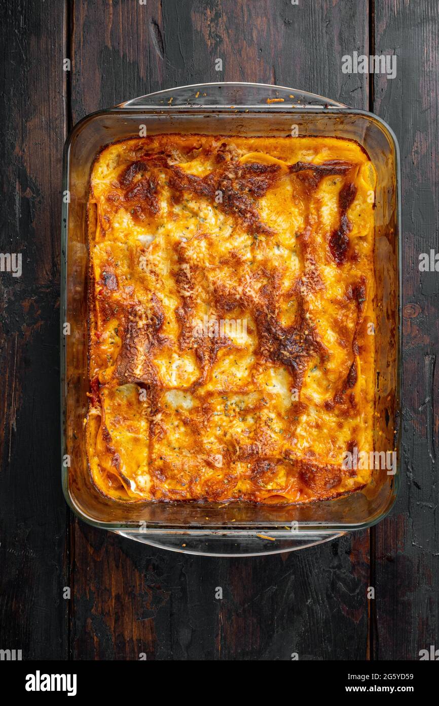 Lasagne tradizionali a base di salsa bolognese di manzo tritato con foglie di basilico, in teglia, su vecchio sfondo di legno scuro, vista dall'alto, piatto Foto Stock