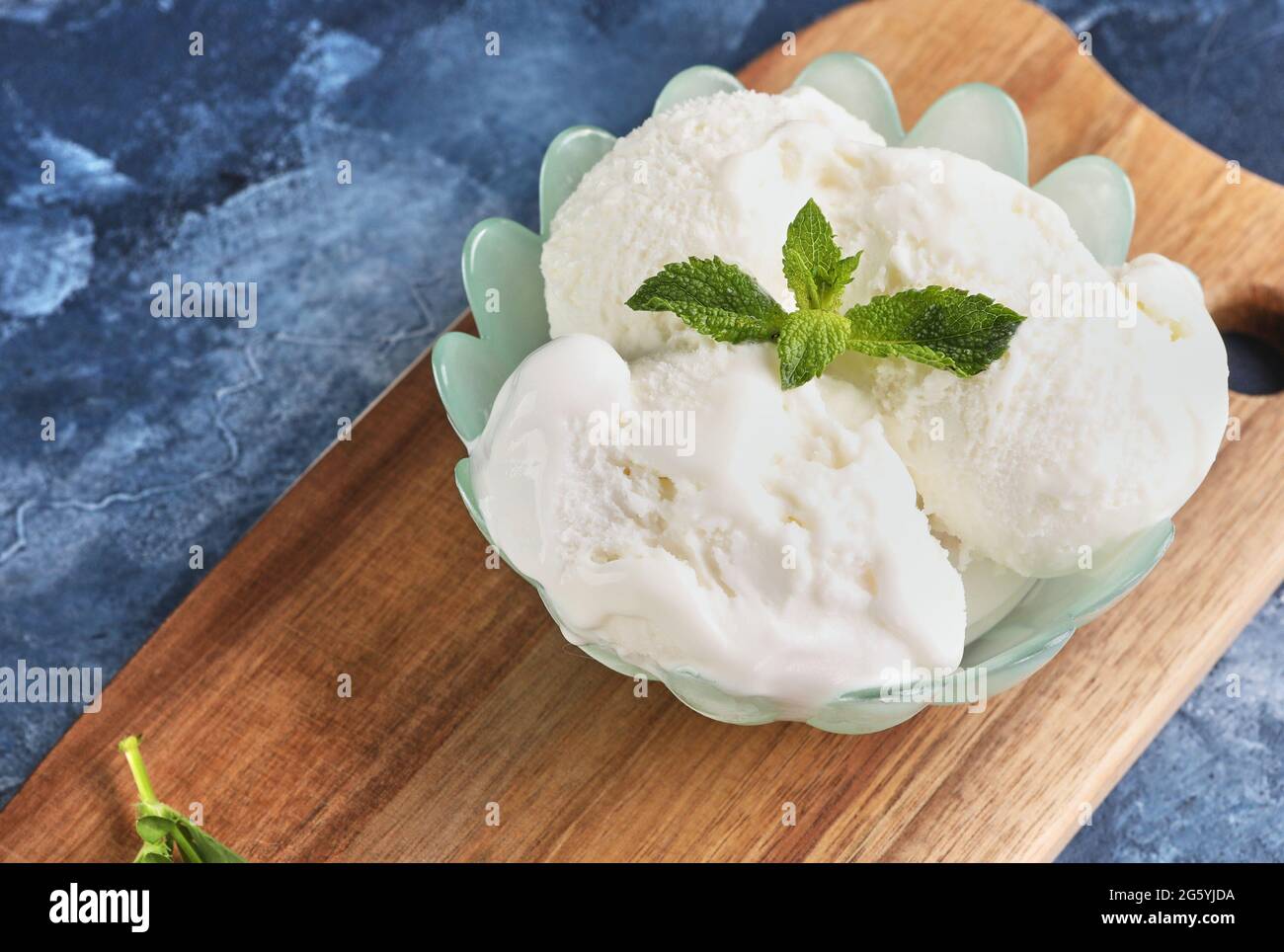 Gelato cremoso in vaso con foglia di menta su sfondo blu Foto Stock