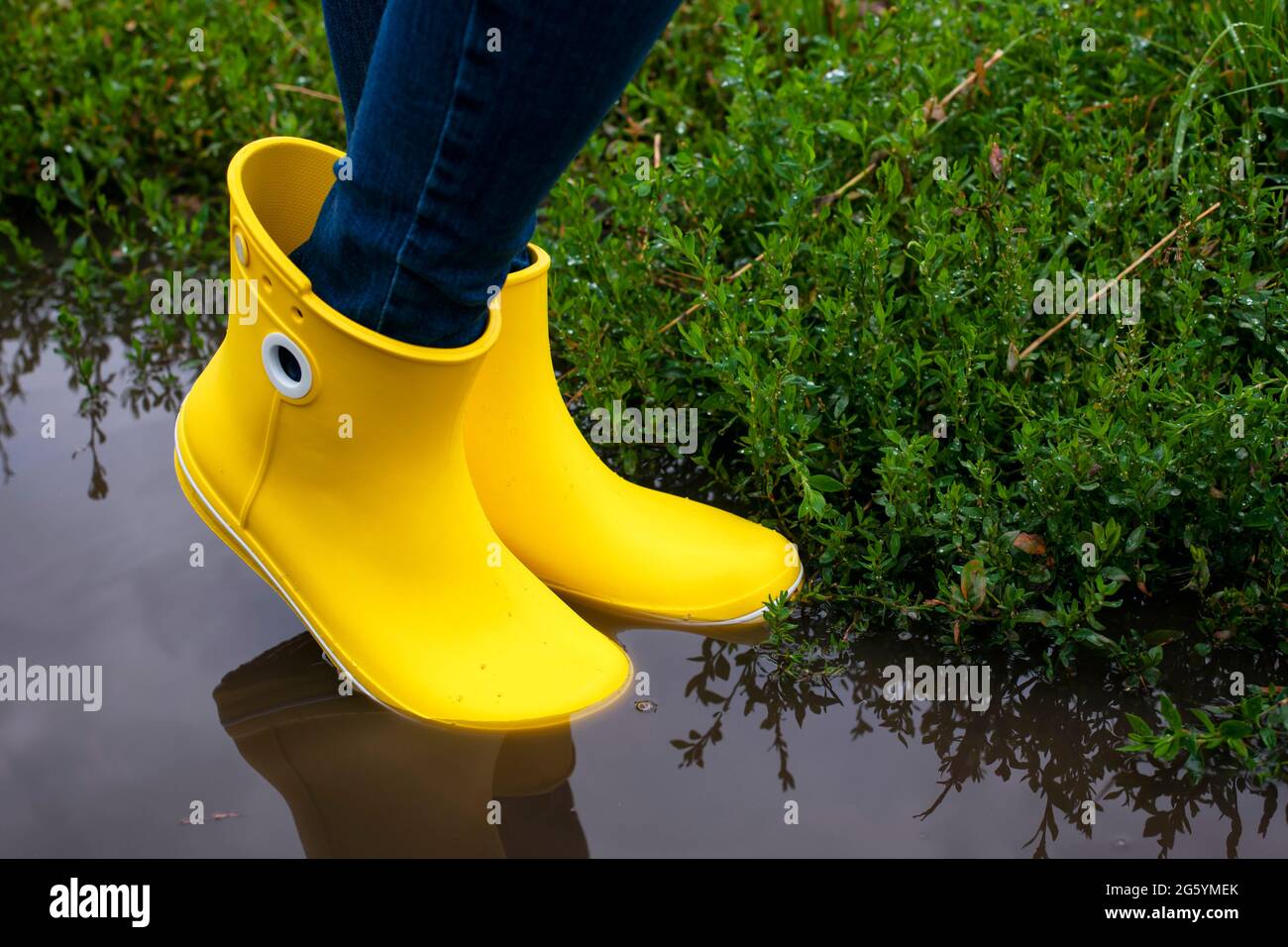 Donna in stivali gialli nel puddle dopo la pioggia. Primo piano Foto stock  - Alamy