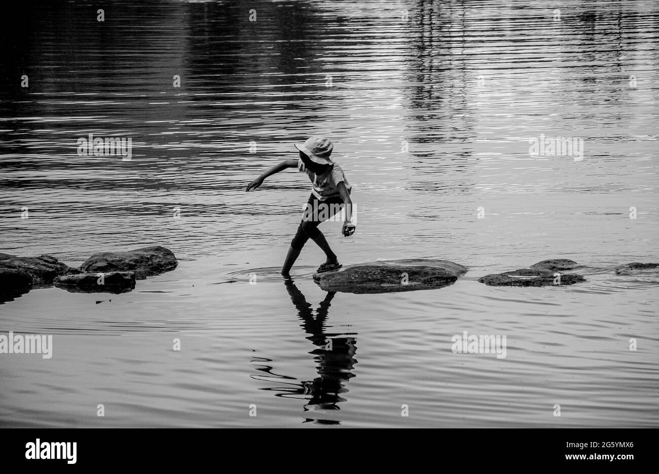 Un bambino cammina lungo la riva del fiume a Sembuwaththa sri lanka. Immagine in bianco e nero Foto Stock