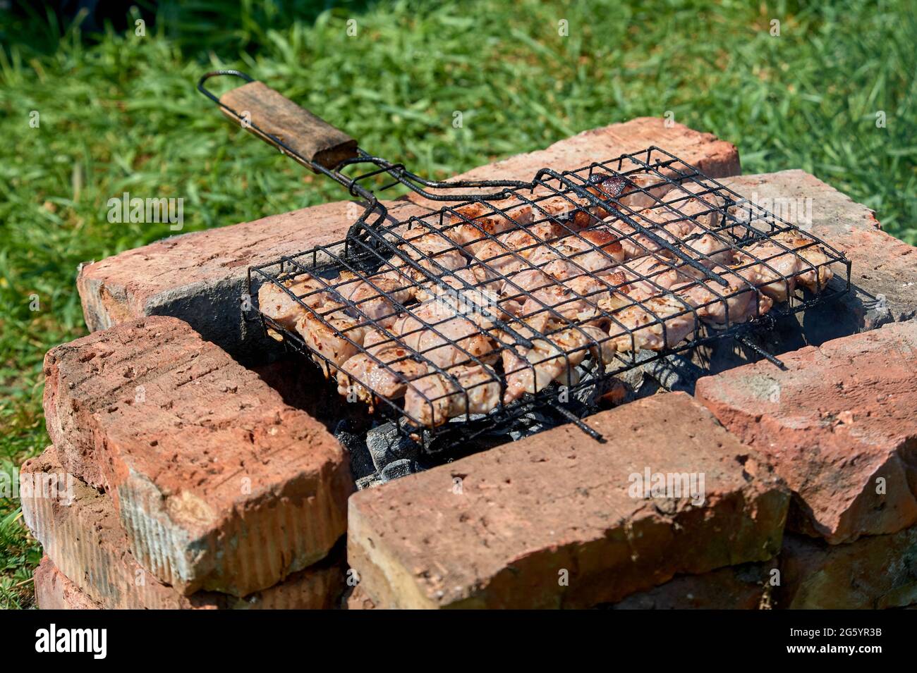 Shish kebab è fritto su una griglia su carboni e mattoni Foto Stock