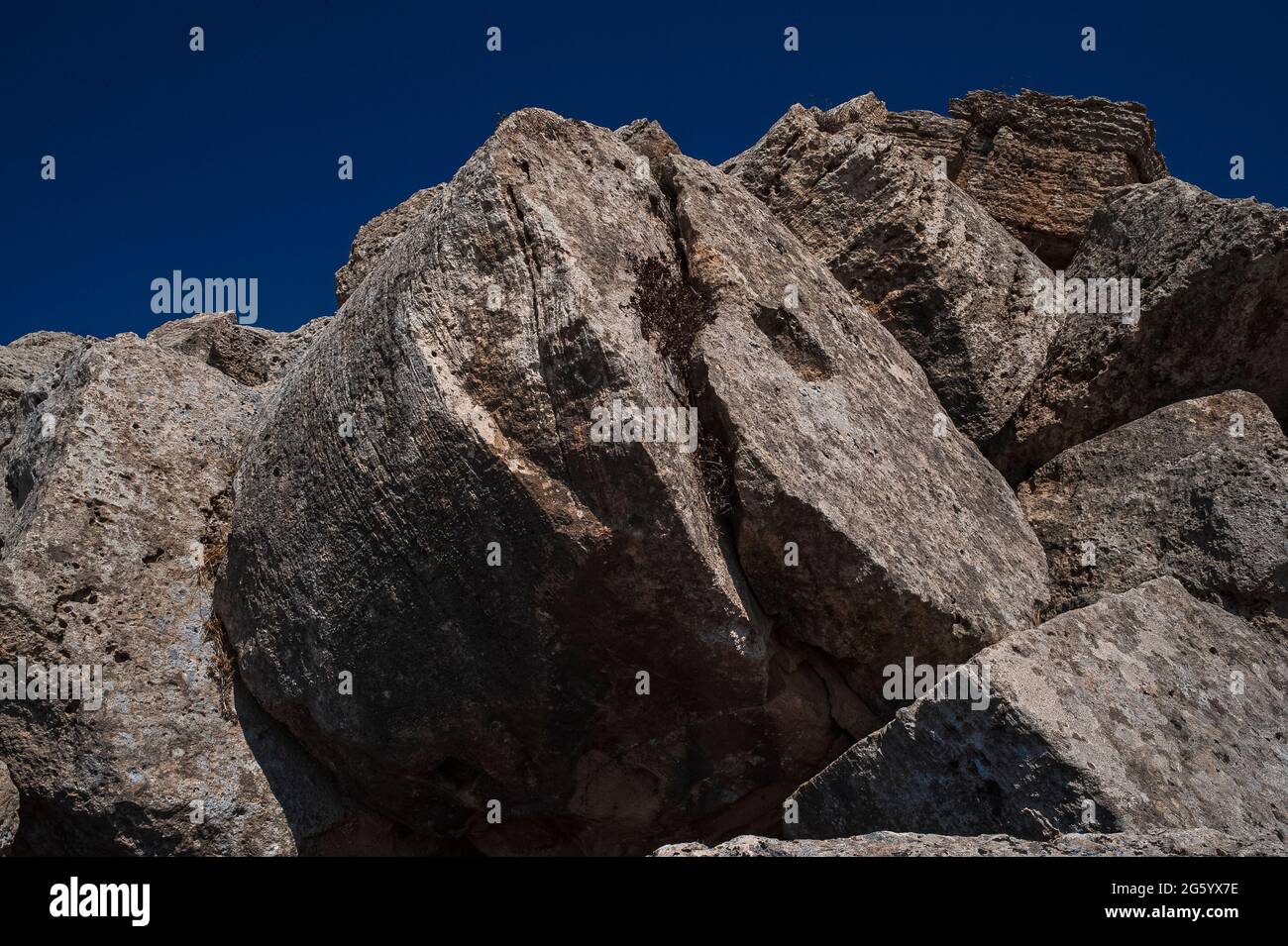 Tamburi di massicce colonne cadute e blocchi di pietra tagliata giacciono tra le rovine di un tempio dorico crollato dedicato ad Apollo o a Zeus sul sito dell'antica città greca e porto di Selinus o Selinous a Selinunte sulla costa sud-occidentale della Sicilia, Italia. La struttura, conosciuta come Tempio G, fu fondata nel 530 a.C. e fu ancora incompiuta quando Selino fu catturato e saccheggiato da Cartagine nel 409 a.C. Il suo crollo era probabilmente dovuto a terremoti nell'era medievale. Foto Stock