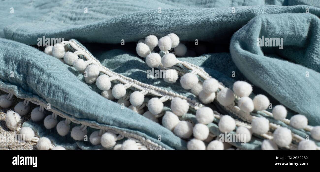 Telo di mussola con treccia con pomposi. Tessuti per la casa per il corpo in cotone biologico. Foto Stock