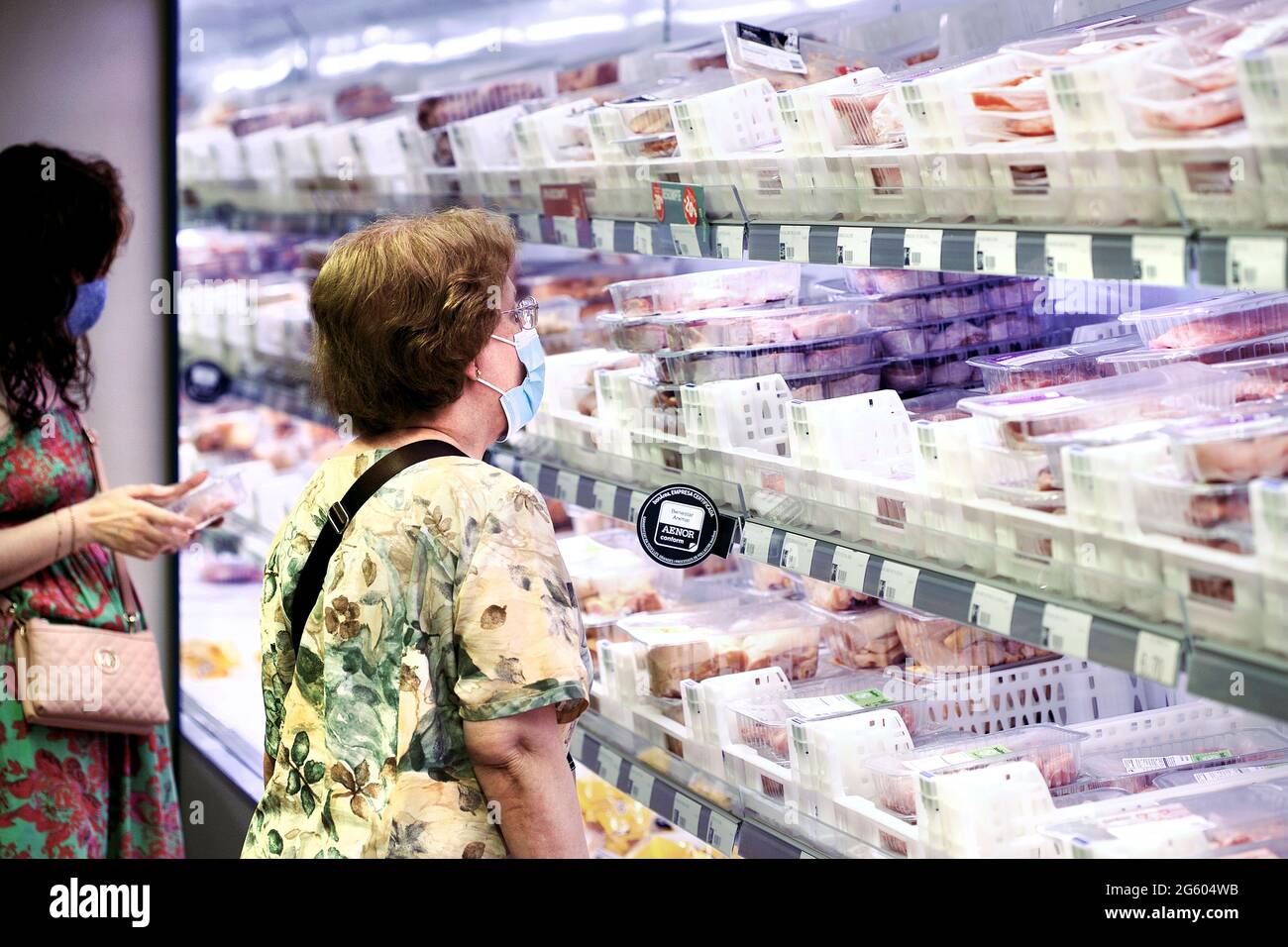 Donne al frigorifero di carne di un supermercato locale, Barcellona, Spagna. Foto Stock