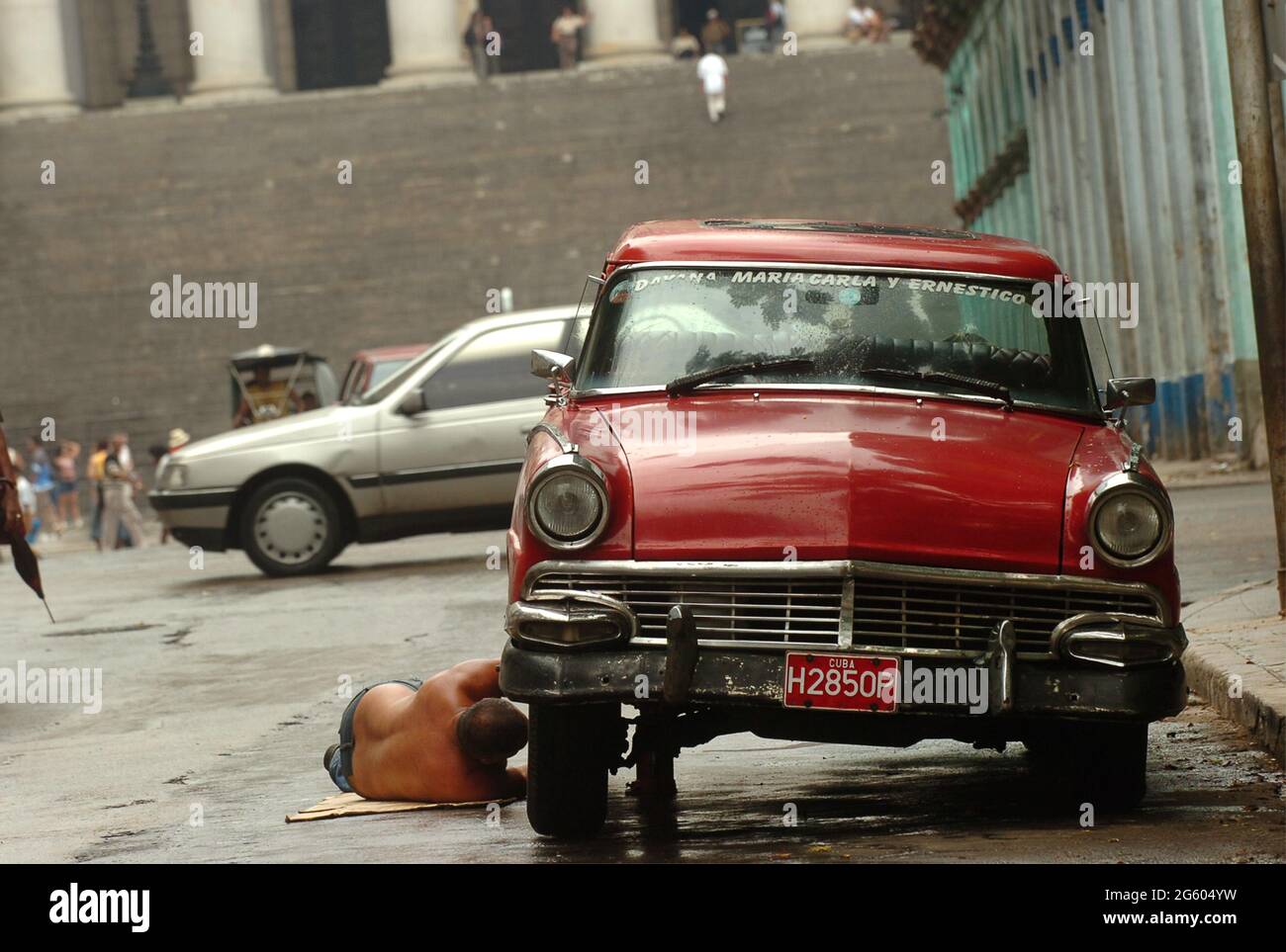 Uomo che ripara la sua vecchia auto per le strade di l'Avana, Cuba maggio 2006. Riparazioni riparazioni riparazione manutenzione uomini cubani classica auto d'epoca riparazione guasti Foto Stock