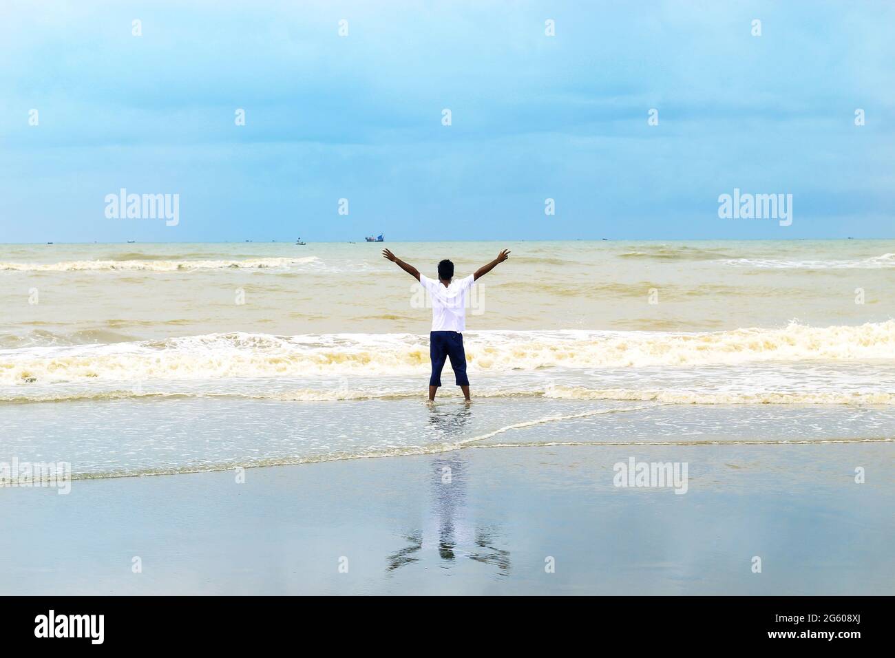 Concetto di successo e di successo. Il ragazzo si gode l'alba sulla più grande spiaggia di mare del mondo - Cox Bazar. Goditi l'alba e le onde del mare. Foto Stock