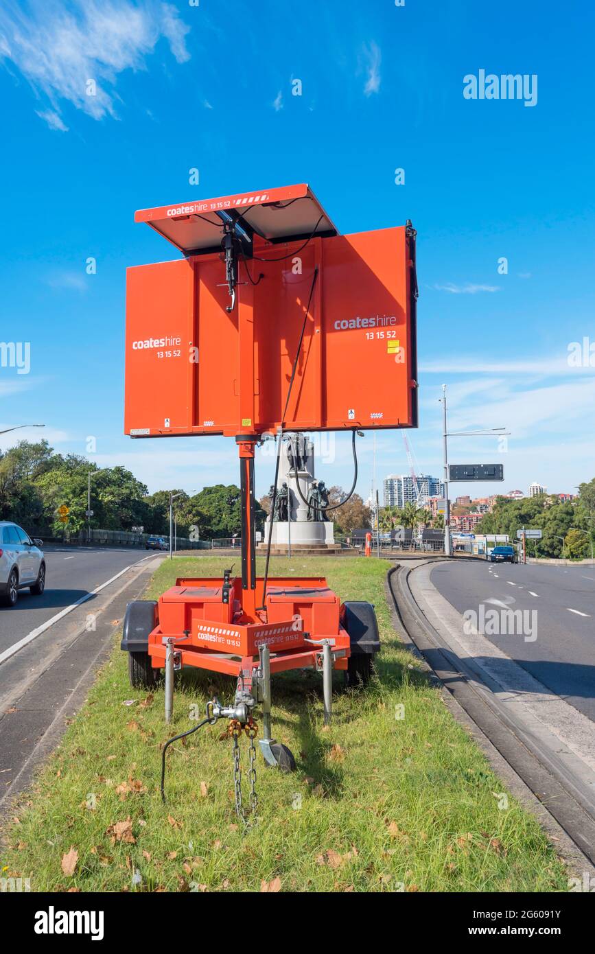 Un pannello di messaggio variabile alimentato a energia solare o un cartello di messaggio sulla striscia di terreno erboso o una strada principale della città di Sydney in Australia Foto Stock