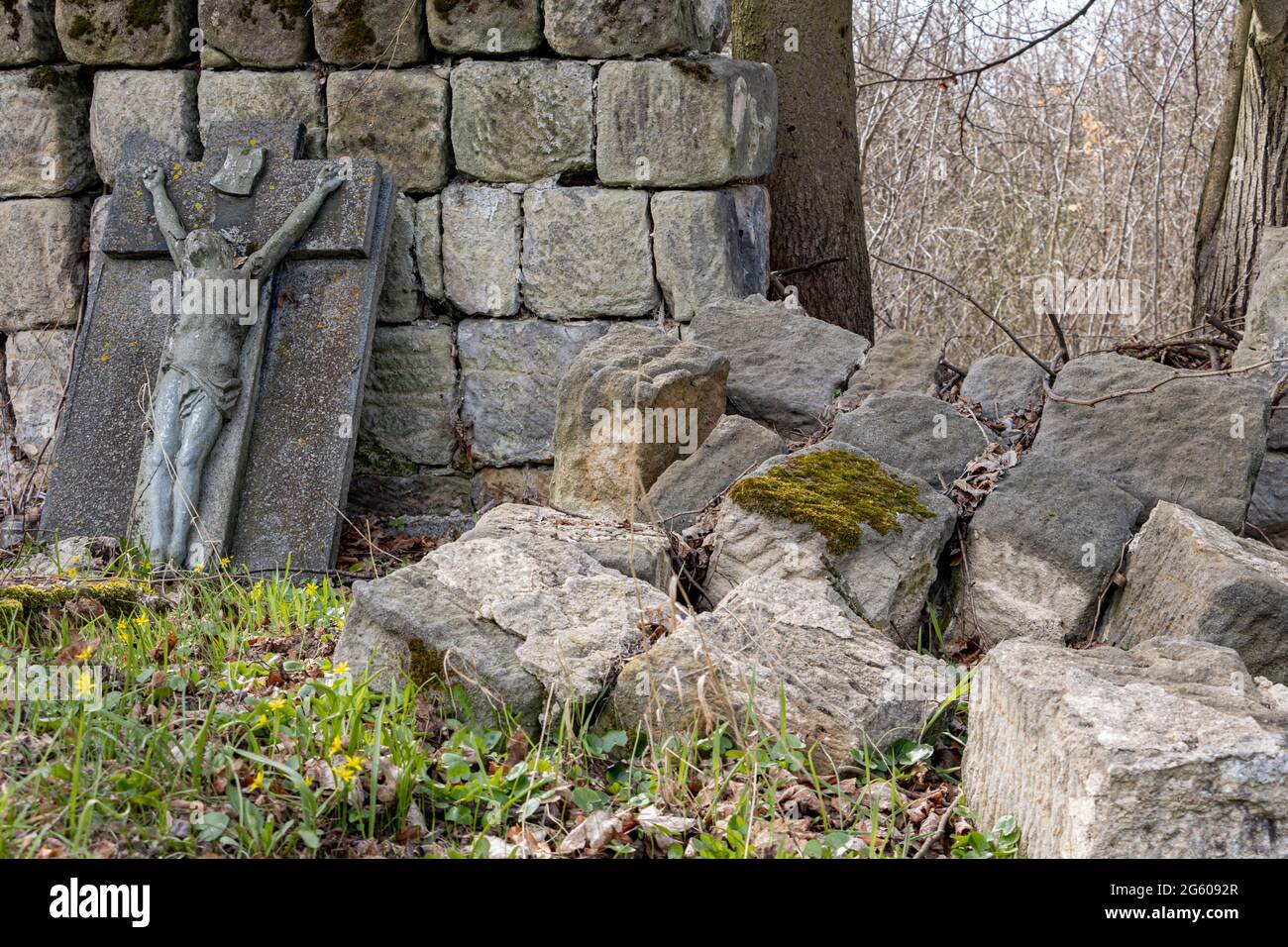 Un muro di pietra demolito con una lapide danneggiata in un cimitero Foto Stock
