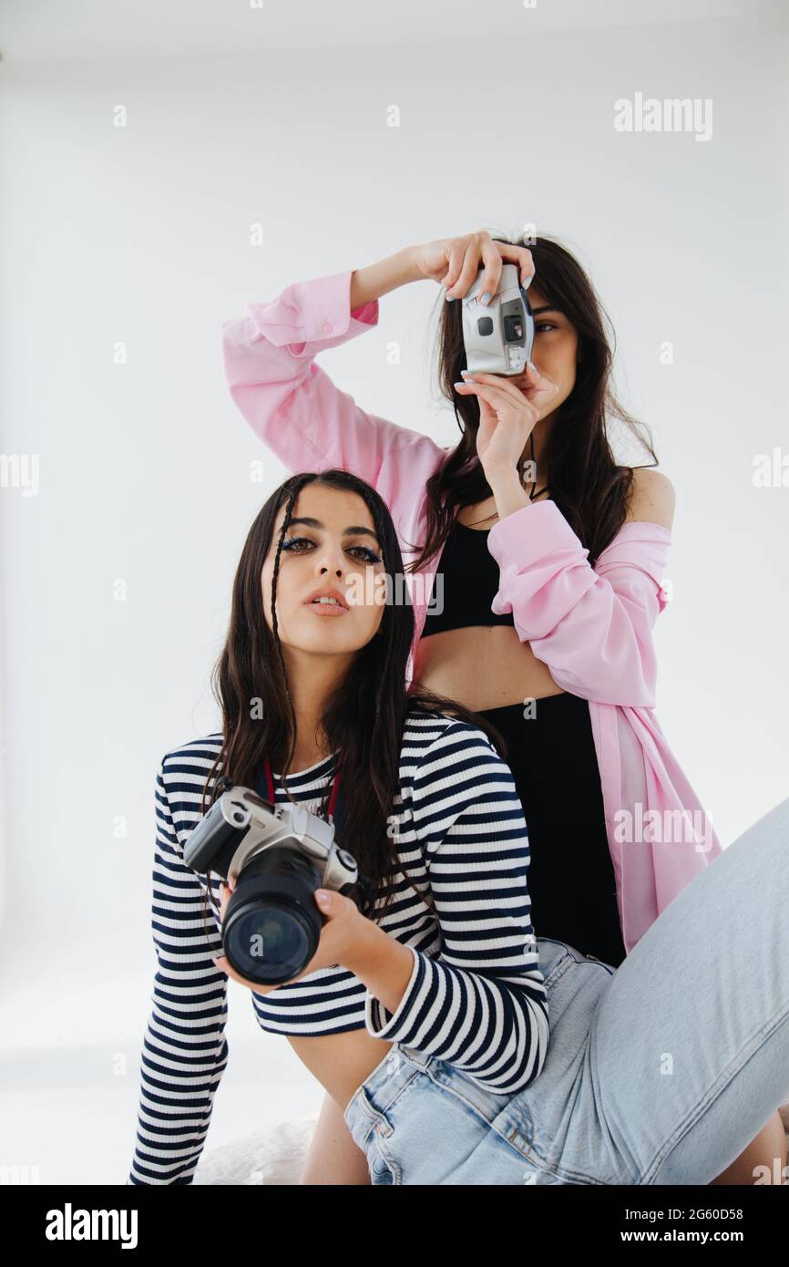 giovani ed eleganti donne armene con macchine fotografiche digitali su sfondo bianco Foto Stock